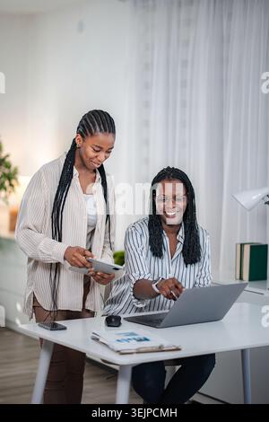 Two black women collaborating business ideas using technology Stock Photo
