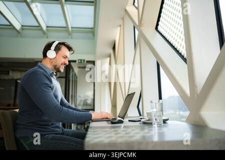 Professional man wearing headphones working on laptop Stock Photo