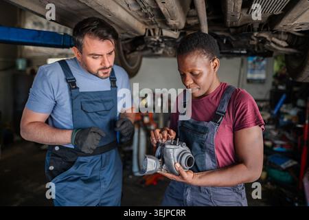 Two mechanics inspecting a turbo in a garage Stock Photo