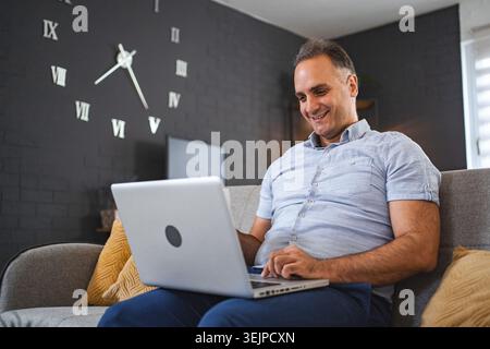 Middle aged Caucasian man using laptop on the sofa Stock Photo