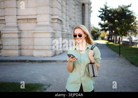 Young woman walking in Vienna using mobile phone Stock Photo