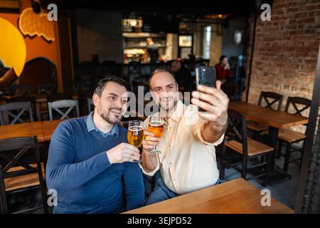 Friends taking selfie at the bar and drinking beer Stock Photo