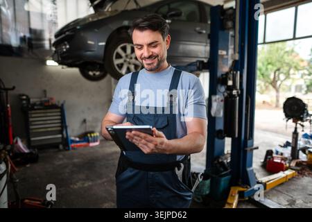 Car mechanic using a digital tablet in a auto repair shop Stock Photo