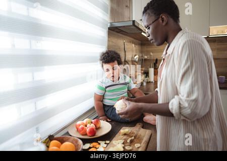 Mother and child preparing healthy fruit snack in kitchen Stock Photo