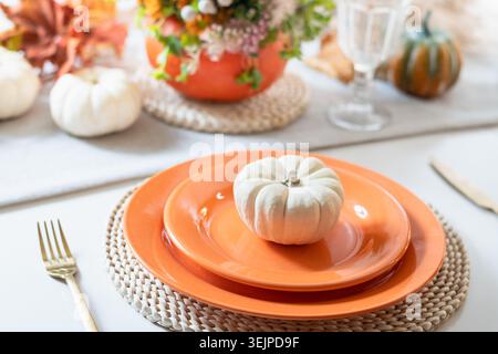 Thanksgiving day table setting with fall decorations of flowers in pumpkin. Stock Photo
