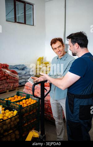 Warehouse workers discussing logistics and inventory on tablet Stock Photo