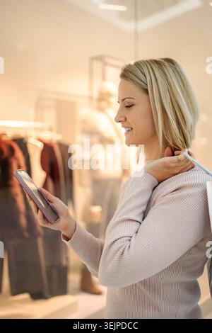 Young adult woman using smartphone while shopping in store Stock Photo