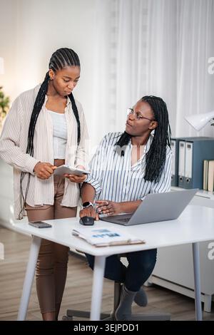 Colleagues collaborating on tablet and laptop in office Stock Photo