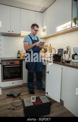 Plumber using digital tablet checking kitchen sink repair Stock Photo