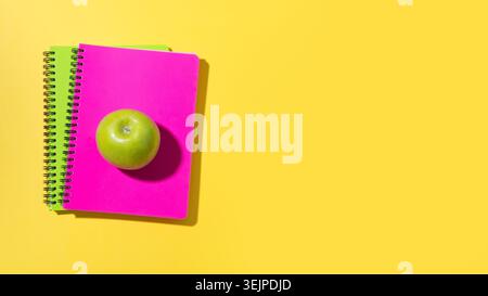 Banner with school supplies, notebooks, green apple on yellow background with copy space. Stock Photo