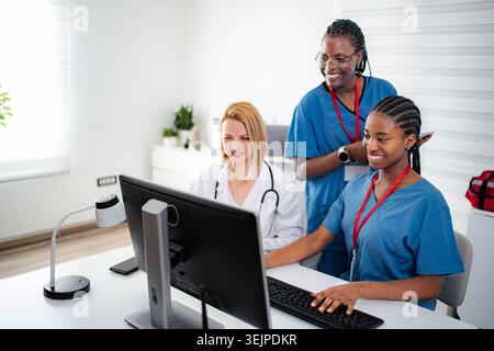 Diverse medical team collaborating on computer in healthcare office Stock Photo