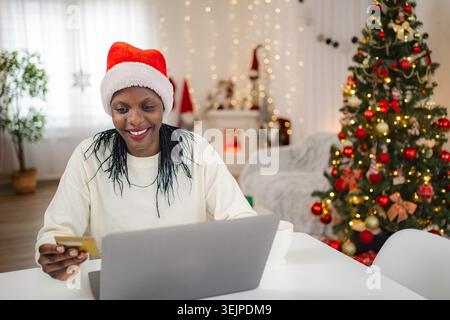 Woman in Santa hat doing Christmas online shopping with credit card Stock Photo