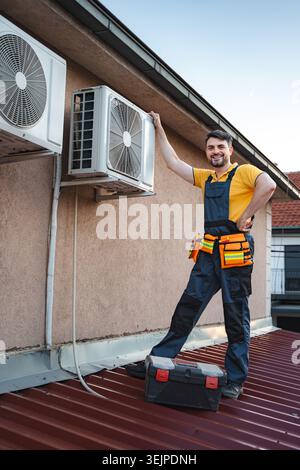HVAC technician installing an air conditioner on a roof Stock Photo