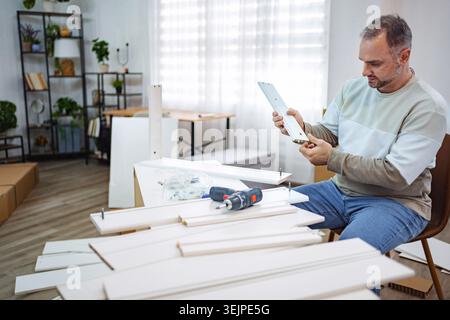 Man assembling furniture in a bright modern room while focused Stock Photo
