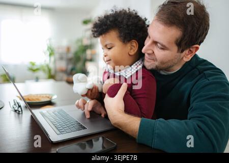 Father and baby son using laptop together at home Stock Photo