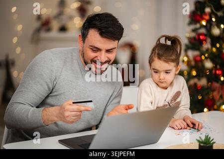 Father and daughter using a laptop for Christmas online shopping Stock Photo