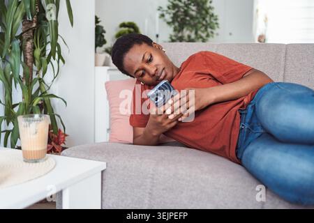 Young woman relaxing on the sofa using her smartphone Stock Photo