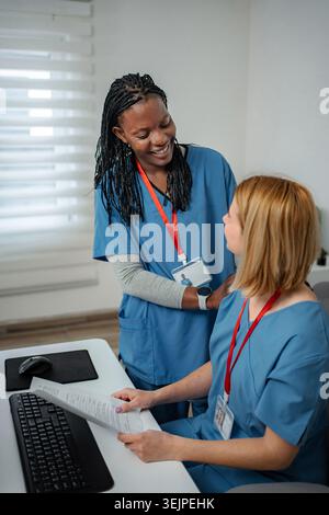 Diverse nurses collaborating on paperwork in modern office Stock Photo