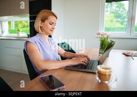 Working woman focused on her laptop over morning coffee Stock Photo