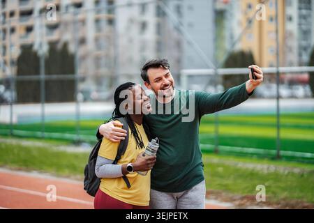 Diverse couple taking selfie on athletics track after workout Stock Photo