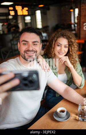 Couple taking a selfie while having coffee in a cafe Stock Photo