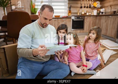 Father reading a story to daughters in a cozy home setting Stock Photo
