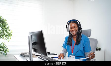 Healthcare professional working on computer, wearing headset Stock Photo