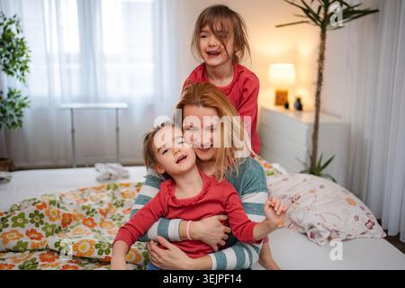 Mother and daughters playing and bonding in bedroom Stock Photo