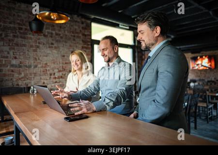 Business colleagues collaborating on laptop during informal meeting Stock Photo
