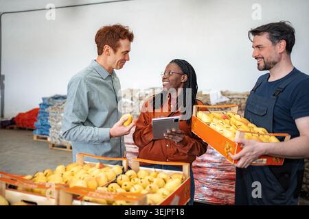 Diverse team checking fresh produce quality in warehouse Stock Photo