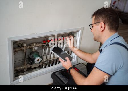 Technician working on underfloor heating system using digital tablet Stock Photo