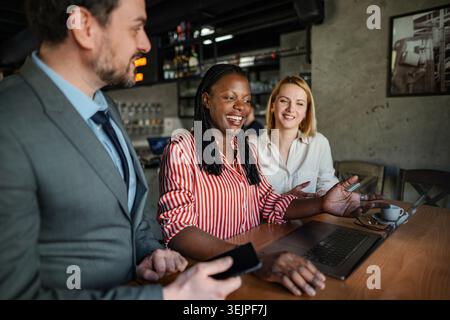 Diverse business team collaborating on laptop in a cafe Stock Photo