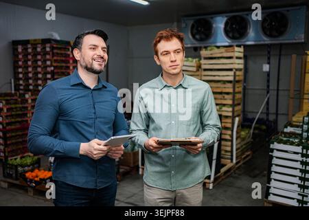 Produce managers inspecting inventory in cold storage warehouse Stock Photo
