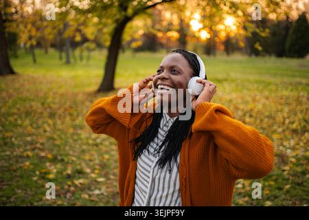 Happy woman enjoying music listening to headphones in park Stock Photo