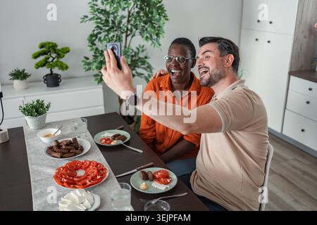 Happy couple taking selfie while having lunch at home Stock Photo