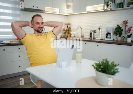 Mid adult man relaxing in kitchen using tablet Stock Photo