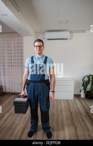 Technician holding toolbox standing in front of air conditioner Stock Photo