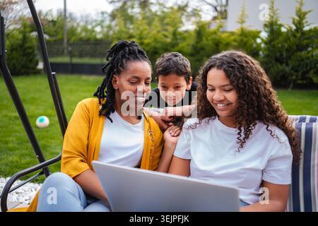 Mother, daughter, son using laptop outdoors in garden Stock Photo