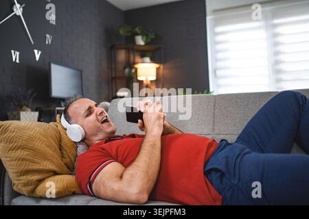 Happy man singing while listening music on the headphonesat home Stock Photo