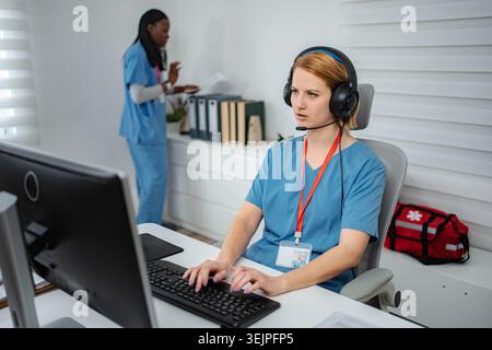 Healthcare employee talking on headset at computer Stock Photo