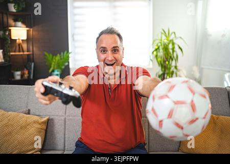 Excited middle-aged man playing video games at home Stock Photo
