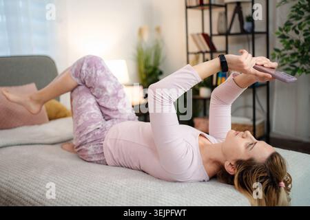 Woman relaxing in bed using smartphone at home Stock Photo