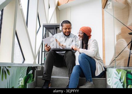 Diverse colleagues collaborating on laptop in modern coworking space Stock Photo