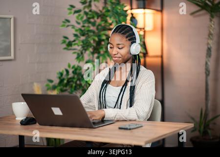 Young black woman wearing headphones using laptop computer Stock Photo