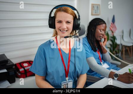 Smiling medical dispatcher wearing headset while working in clinic Stock Photo