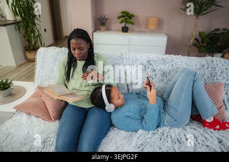 Mother and daughter relaxing on couch at home Stock Photo