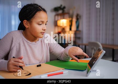 Girl drawing face while using digital tablet for remote learning Stock Photo