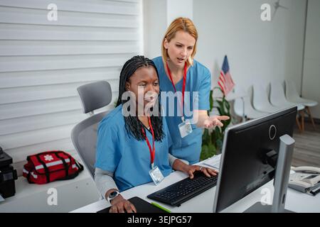 Diverse medical colleagues collaborating on computer in office Stock Photo