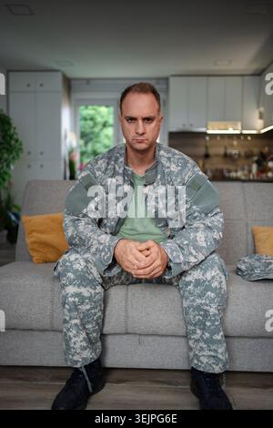 Depressed soldier sitting on sofa at home Stock Photo