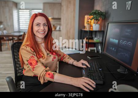 Young businesswoman working from home smiling at camera Stock Photo
